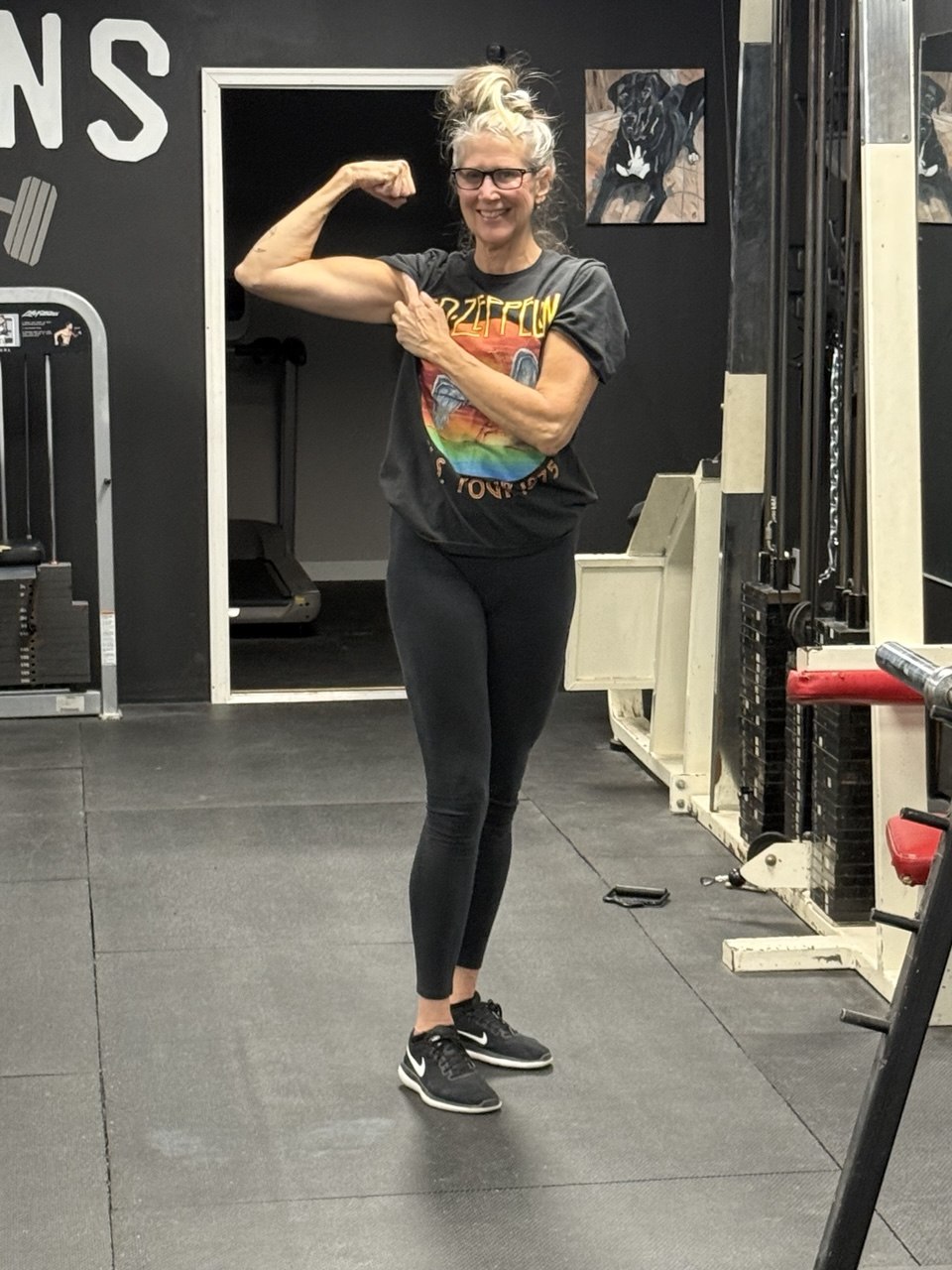 Jean smiling and flexing confidently on the Titans Gym training floor